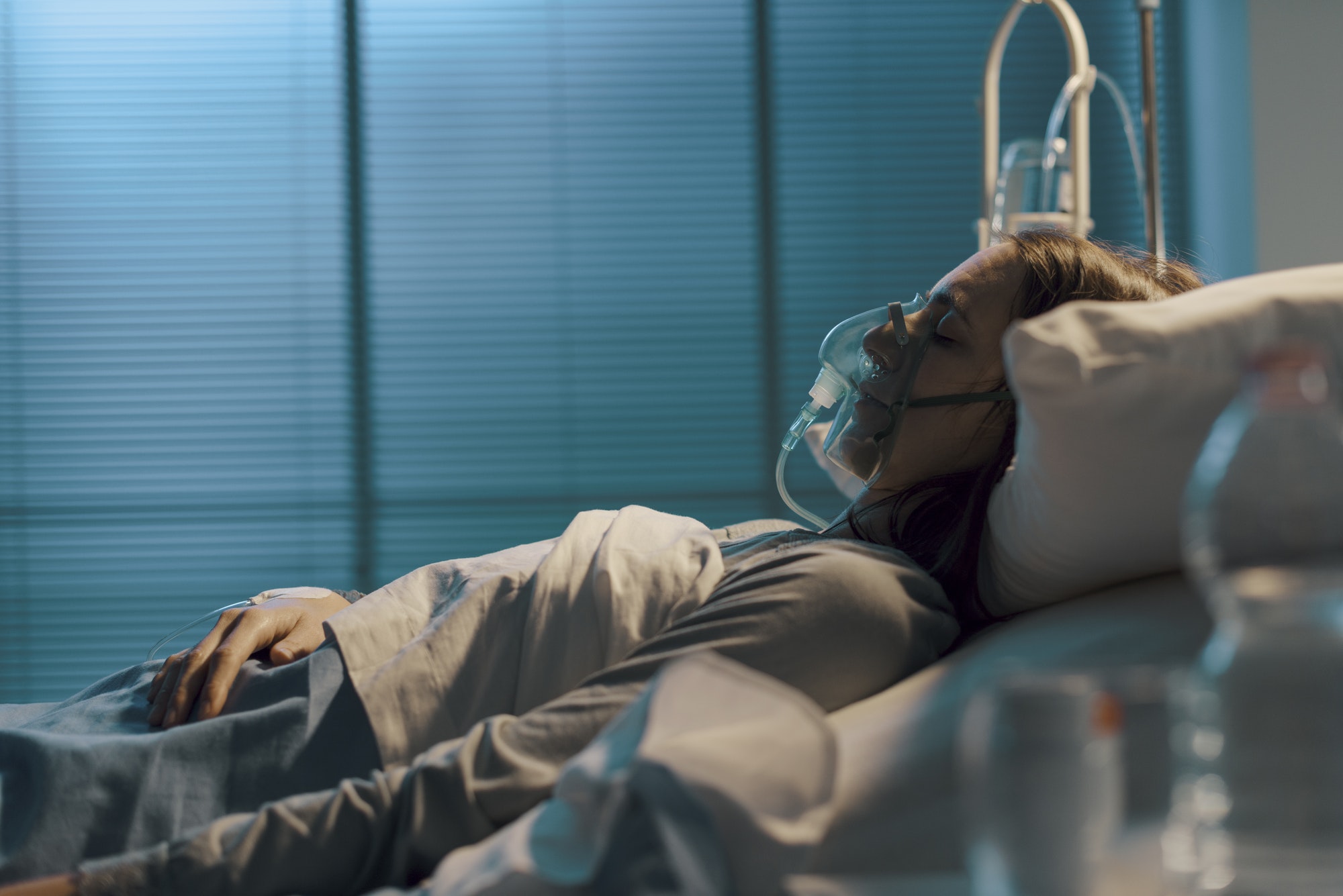 Woman with oxygen mask lying in a hospital bed